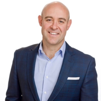 Professional headshot of a smiling man in a navy blue blazer and light blue shirt, against a white background.
