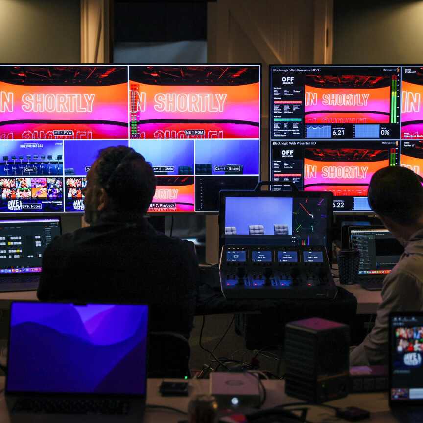 Control room setup for a live event featuring multiple screens displaying various video feeds and countdown timers, with operators managing the production process.
