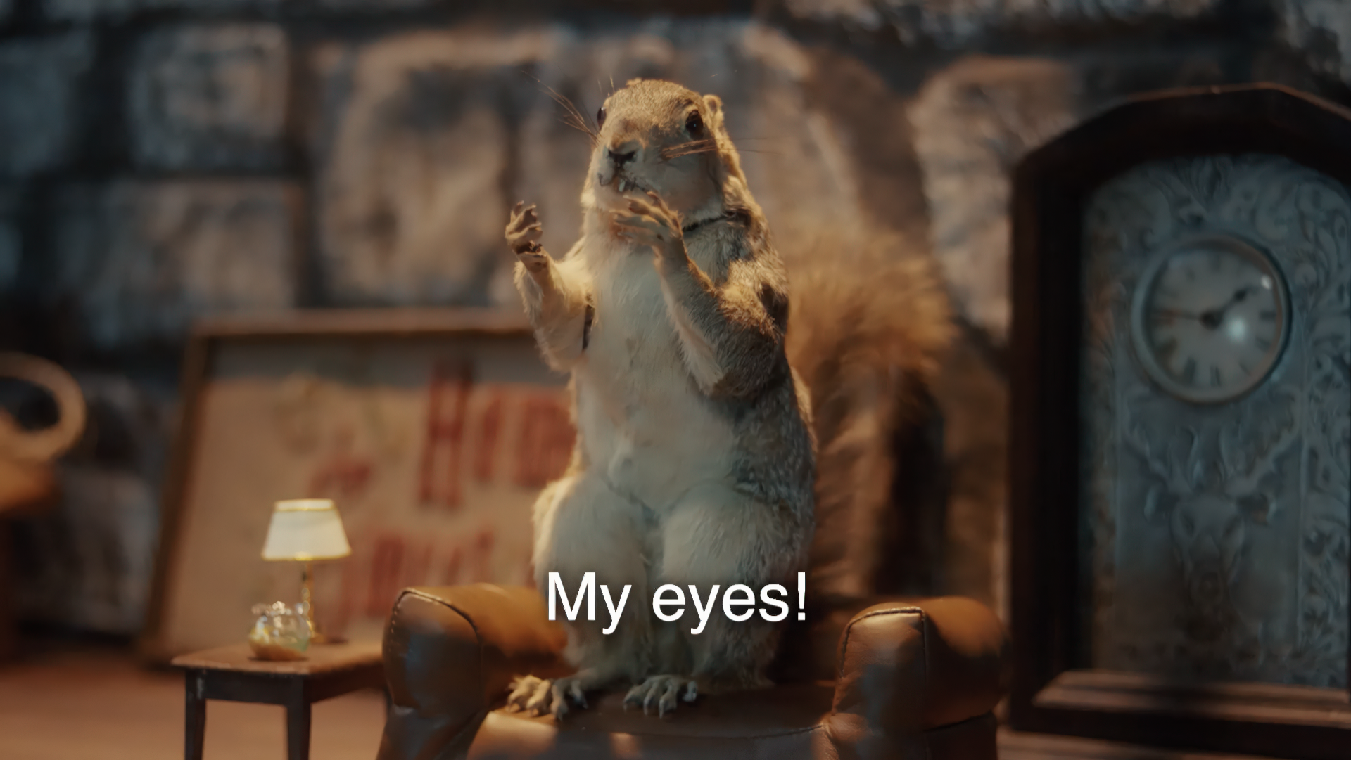 A humorous scene featuring a stuffed squirrel sitting on a small brown chair with a lamp and clock in the background, expressing surprise with its paws raised and a caption that reads "My eyes!"