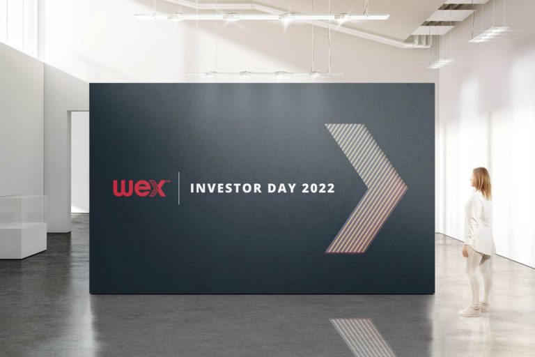 WEX Investor Day 2022 event backdrop featuring the WEX logo and a stylized arrow design in a modern conference setting.